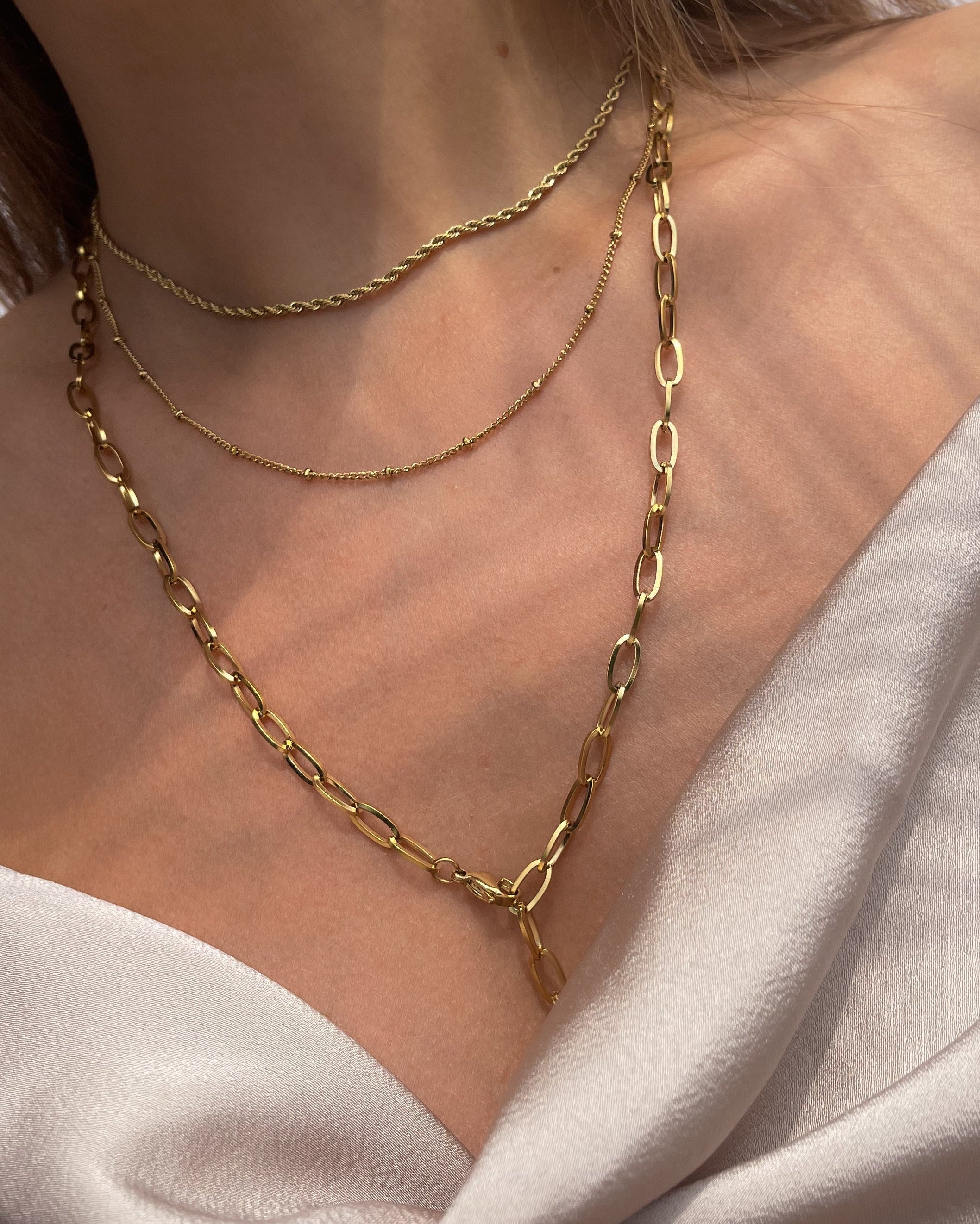 Drei verschiede Edelstahl Ketten in gold, getragen mit beigefarbenen Top. Wasserfest und hypoallergen.