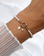 Wasserfester Edelstahl Charm in Muschelform an einem Perlenarmband.