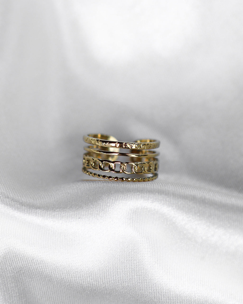 4-lagiger Edelstahl Ring auf weißem Stoff.
