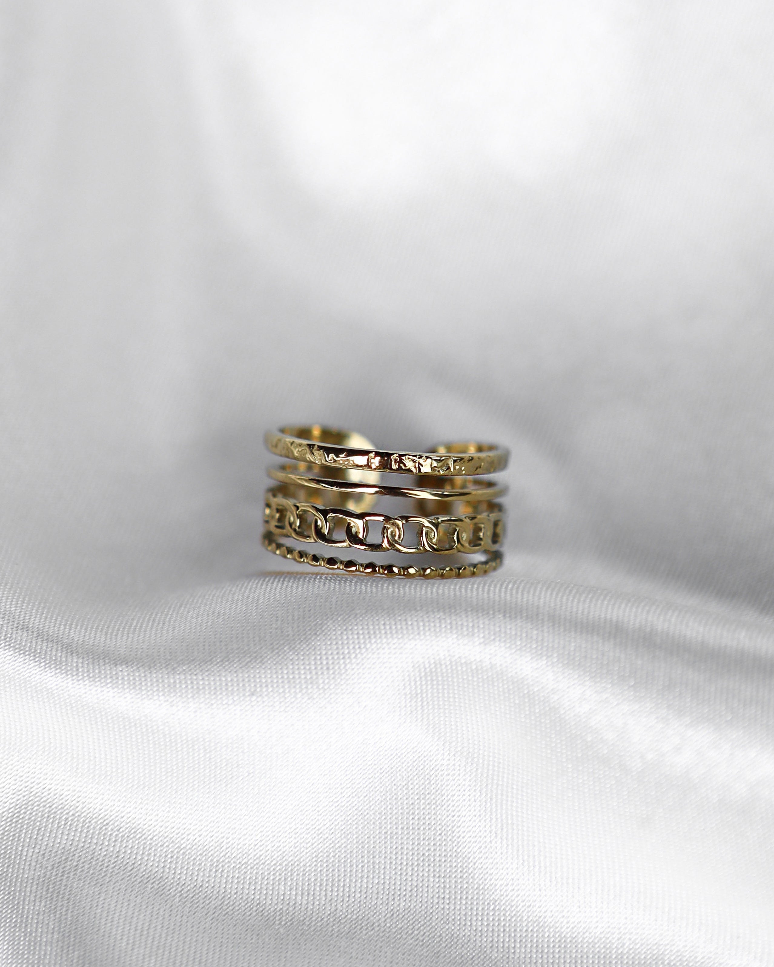 4-lagiger Edelstahl Ring auf weißem Stoff.