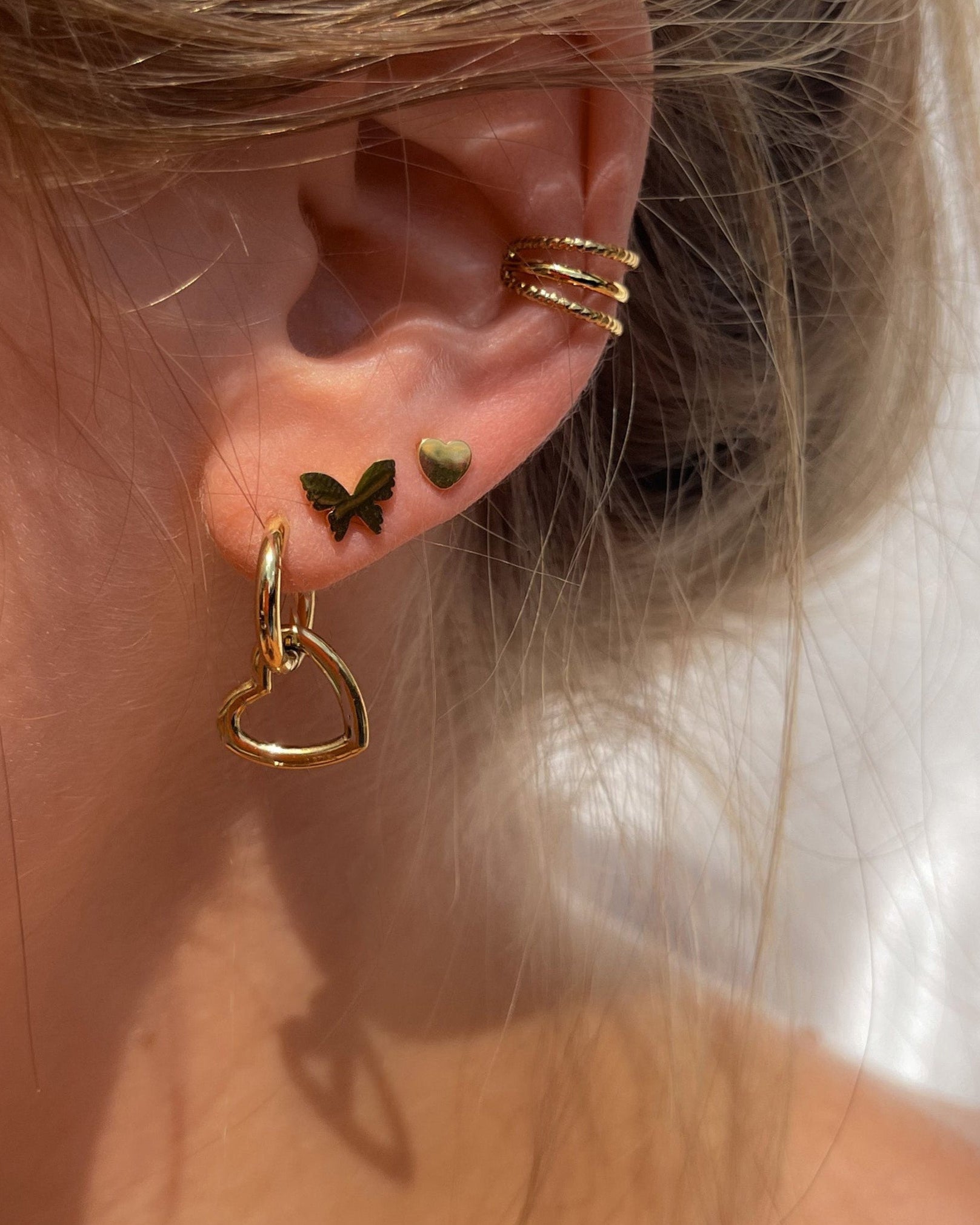 Dreilagiger Edelstahl Earcuff in gold, getragen am Ohr mit anderen Ohrringen.