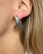 Wasserfeste Edelstahl Ohrstecker in wellenartigem Design in silber, getragen am Ohr.