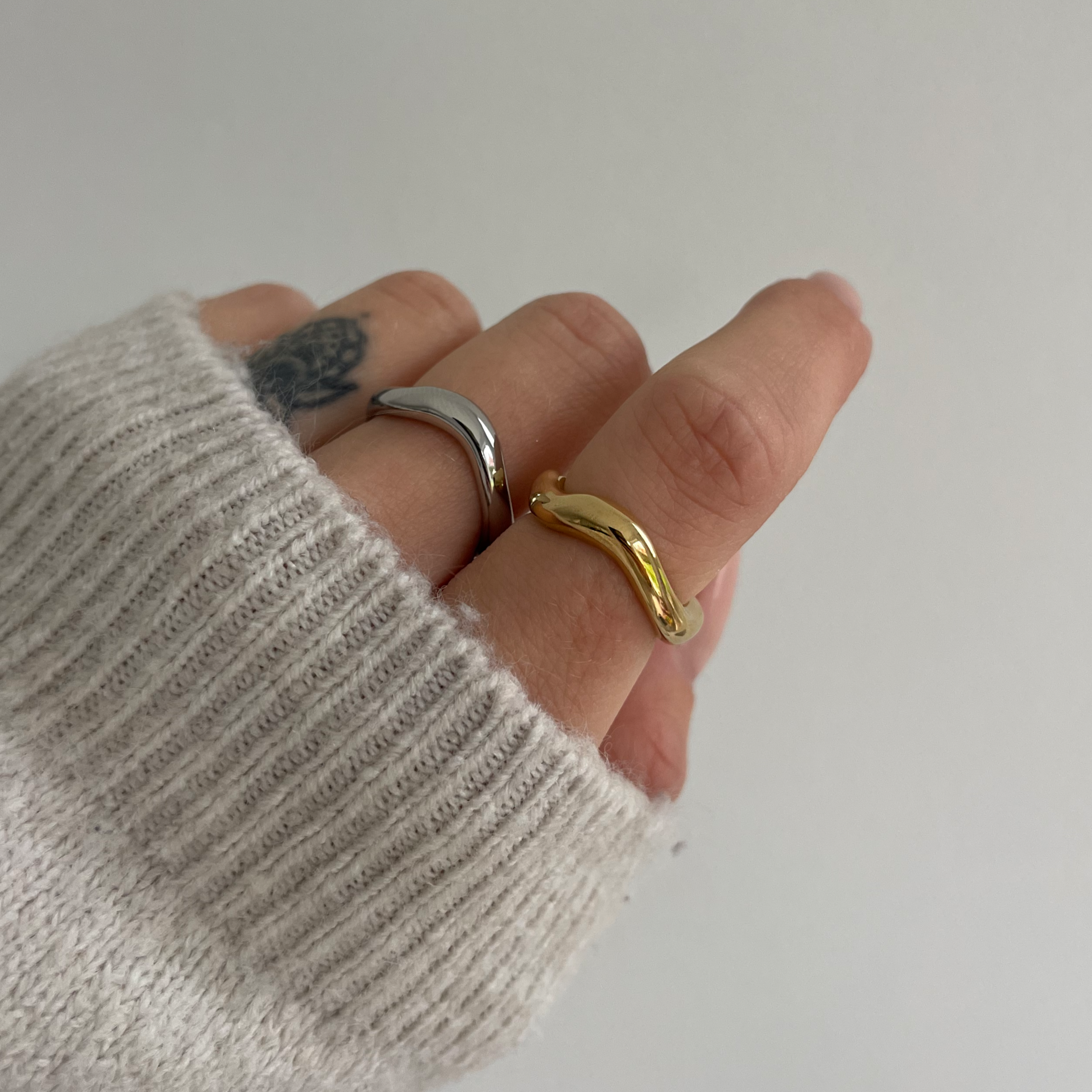 Wasserfester Edelstahl Ring in geschwungenem Design in gold und silber, getragen am Finger.