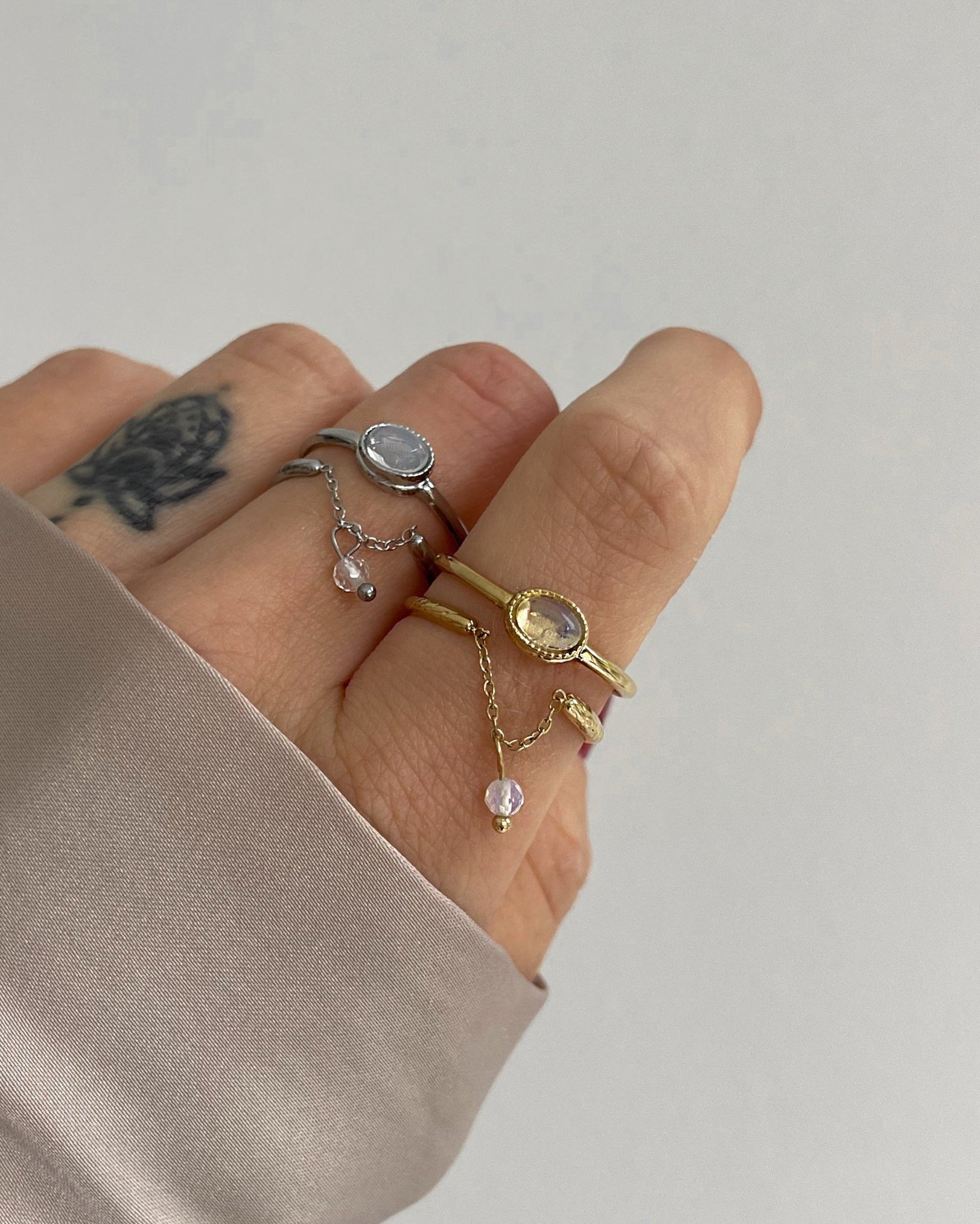 Doppellagiger Ring mit schimmerndem Detail und Kettendesign, getragen am Finger.