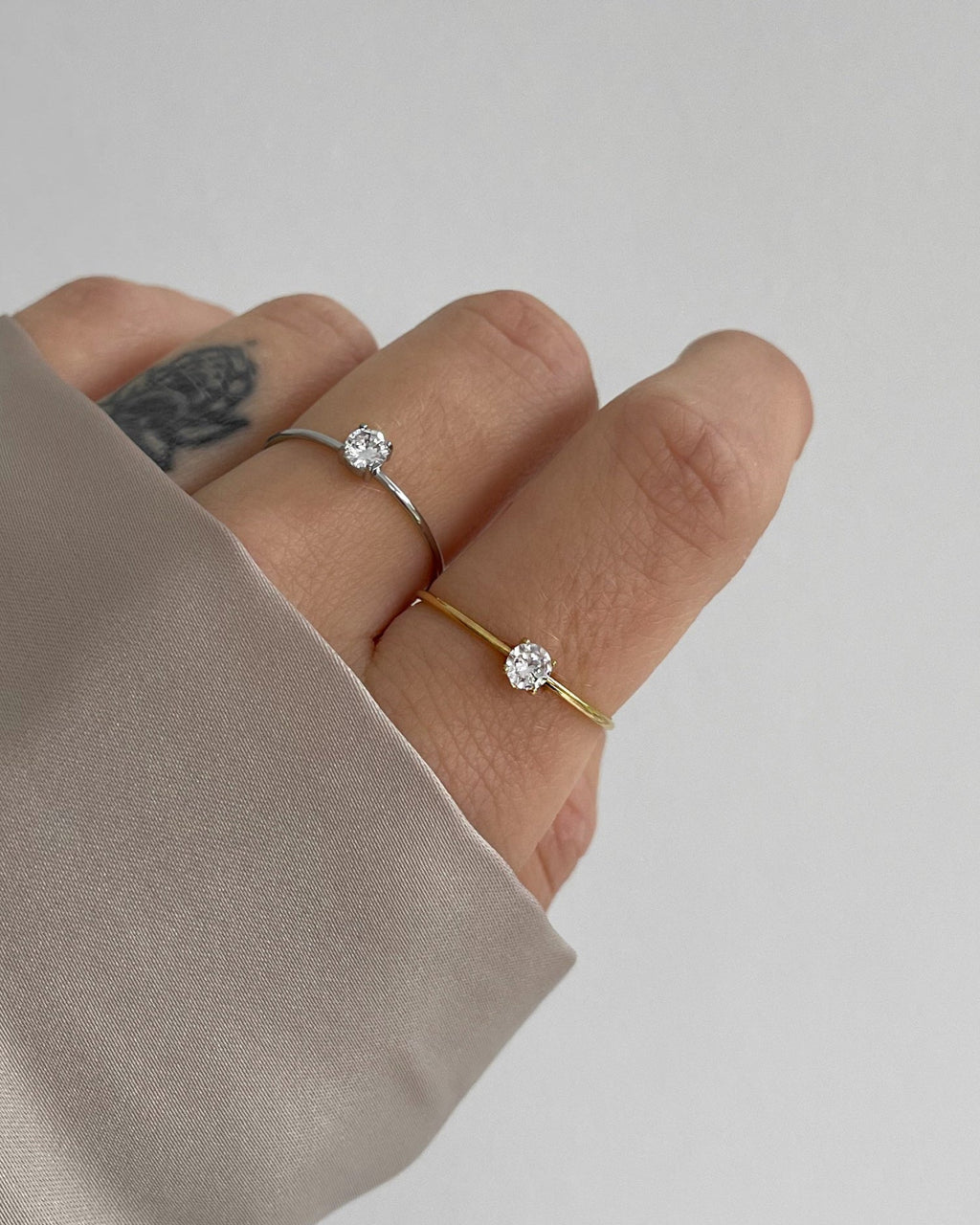 Feiner, schlichter Edelstahlring mit rundem kleinen Zirkonia Stein, getragen am Finger.
