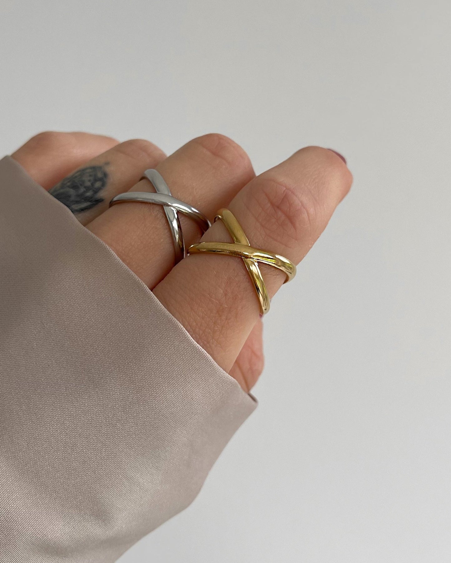 Wasserfester Edelstahl Ring mit gekreuztem Design in gold und silber a Finger getragen.