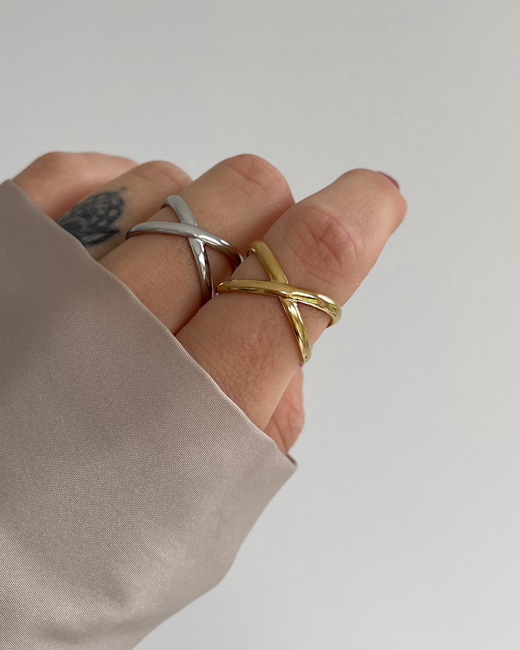 Wasserfester Edelstahl Ring mit gekreuztem Design in gold und silber a Finger getragen.