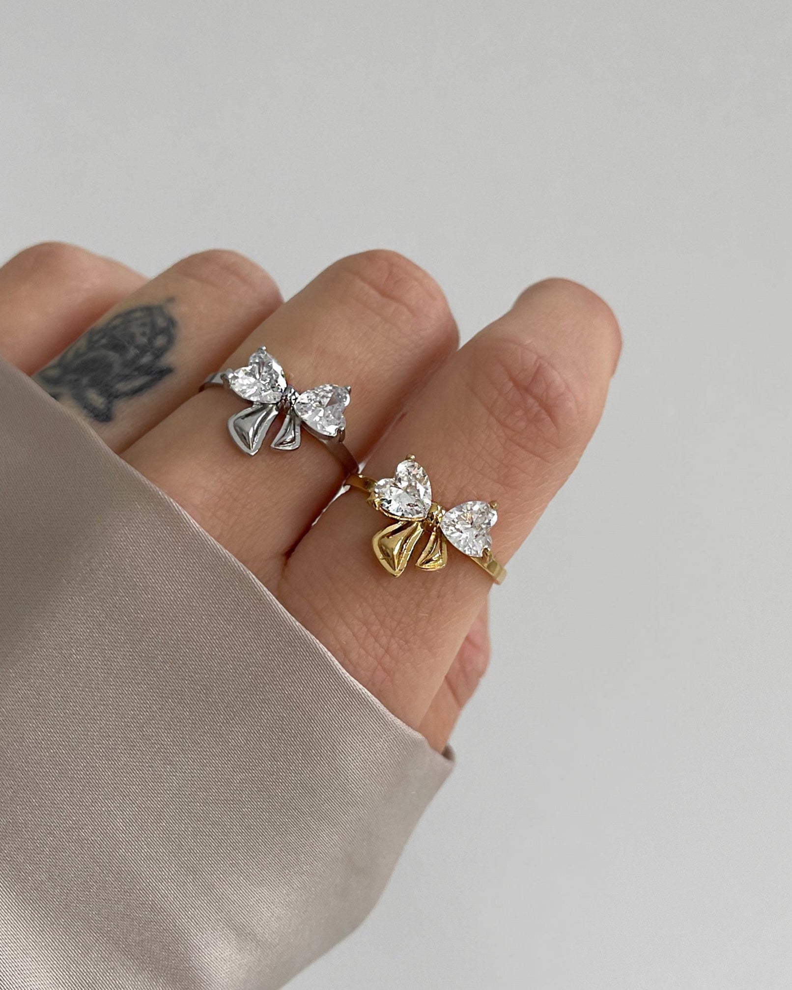 Wasserfester Edelstahlring in Schleifendesign mit großen Herzförmigen Zirkoniasteinen, getragen am Finger.