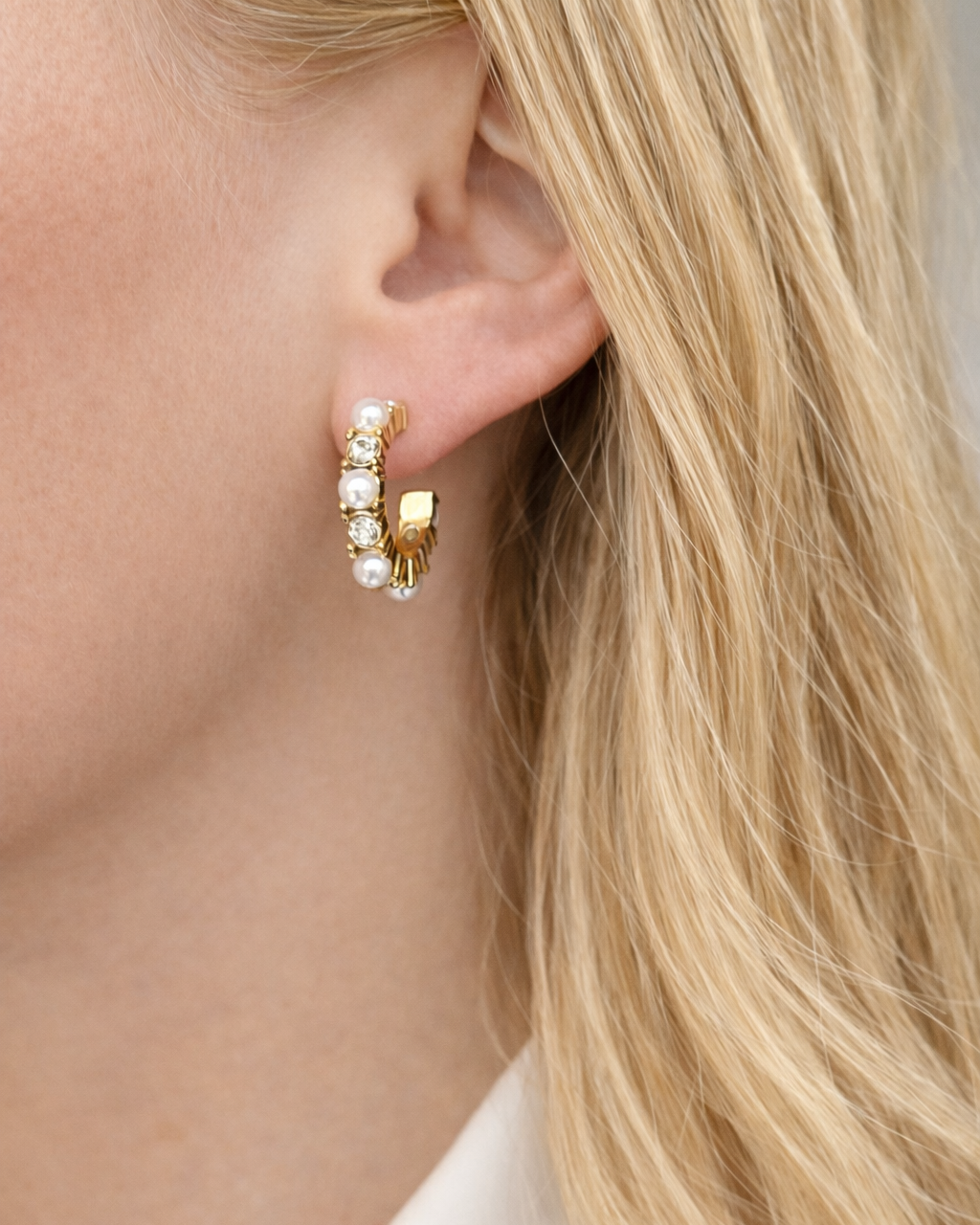 Goldene Pearl Hoops mit Perlen und Zirkonia am Ohr eines blonden Models Nahaufnahme