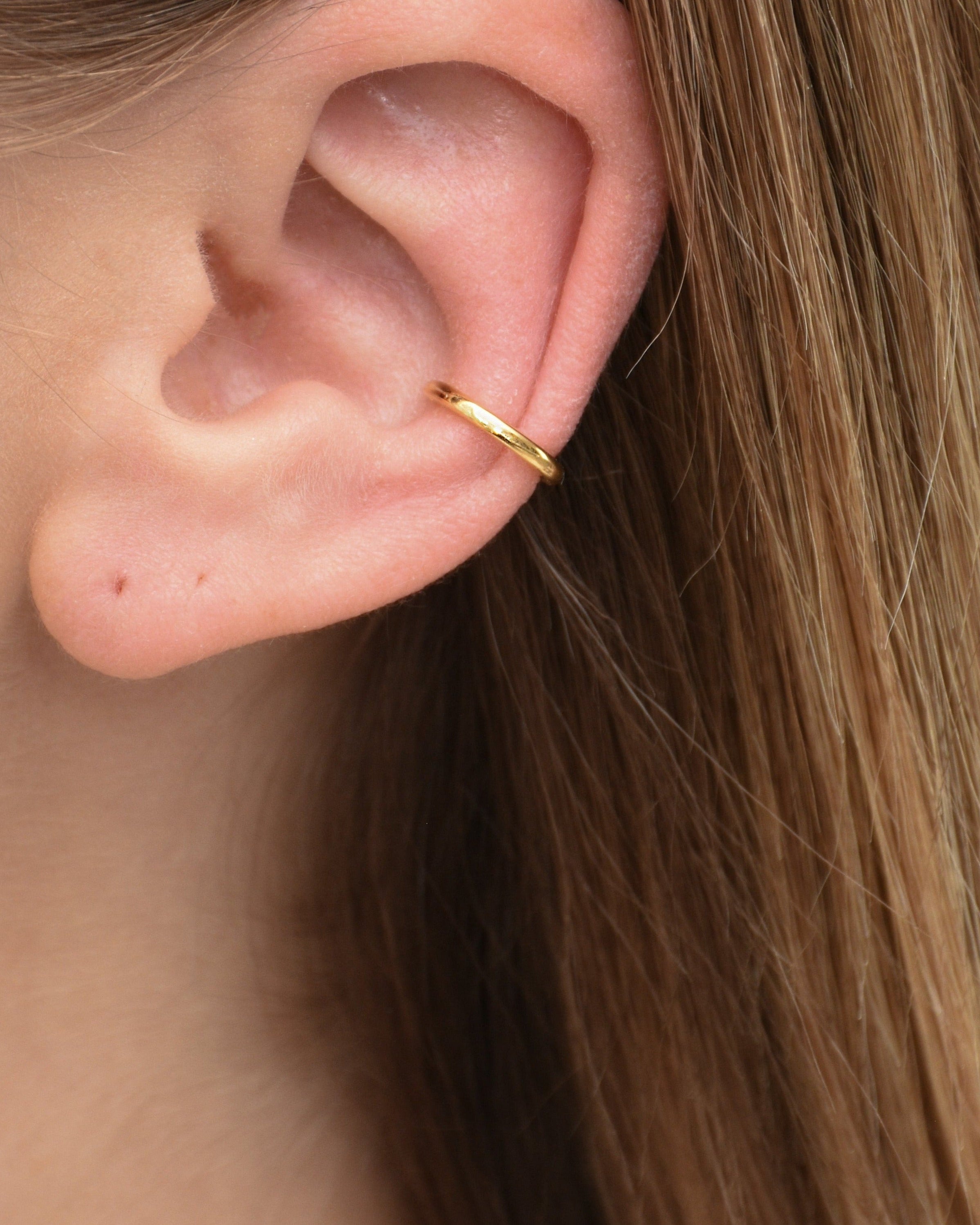 Feiner Edelstahl Earcuff in gold, getragen am Ohr.