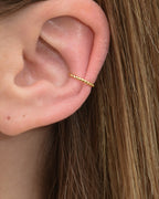 Feiner gedrehter Edelstahl Earcuff in gold getragen am Ohr.